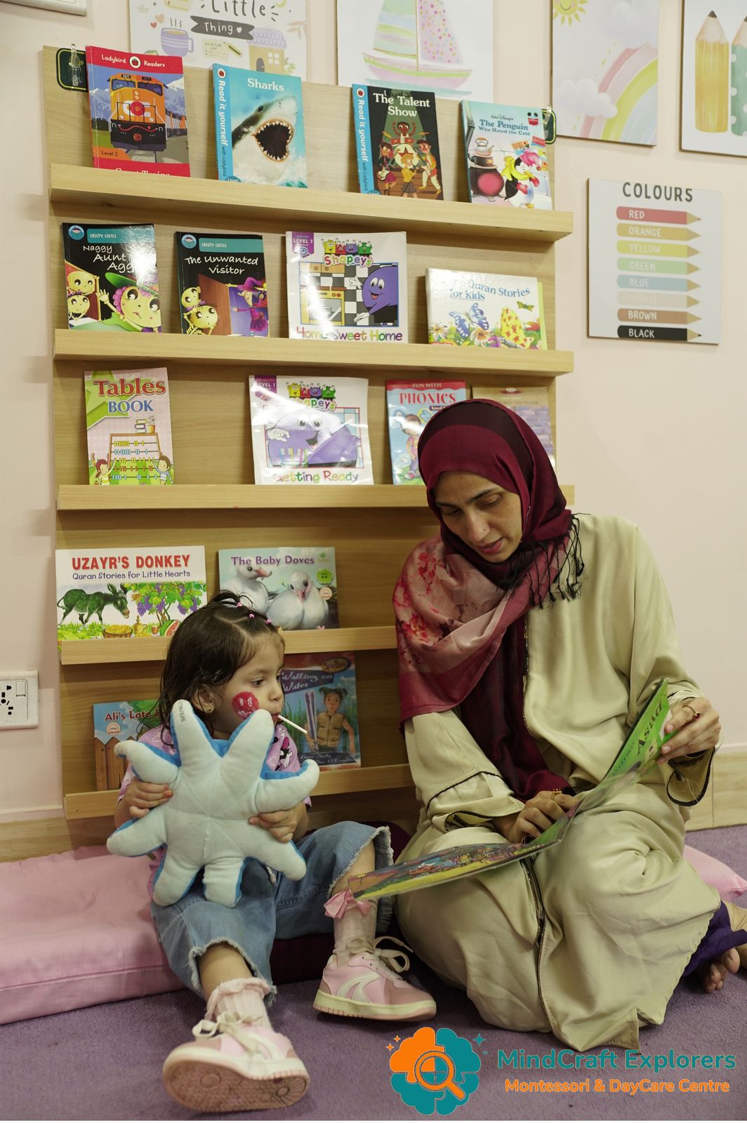 A teacher reading a picture book with a young child in the book corner