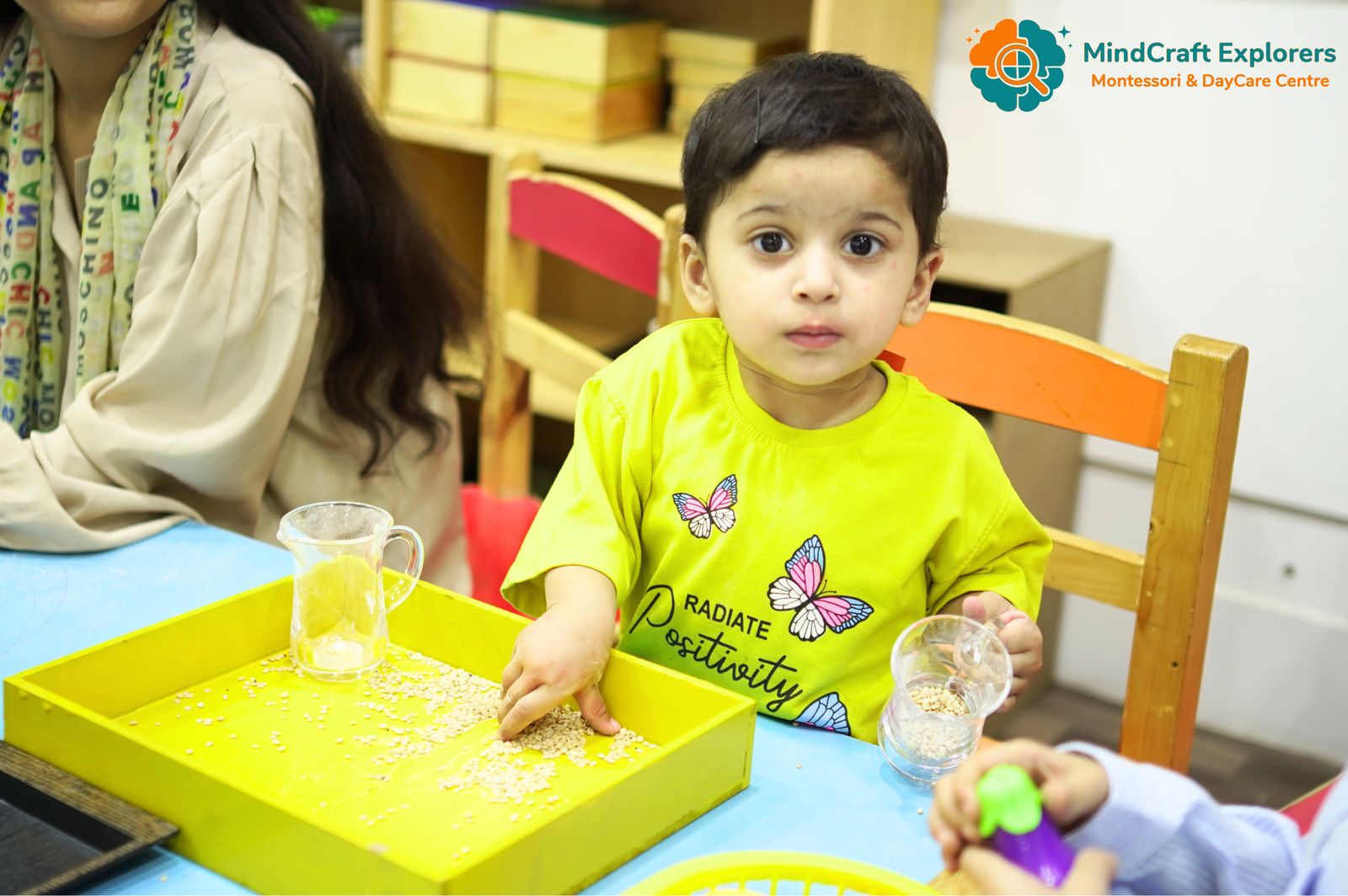 A toddler scooping grains with a small jug